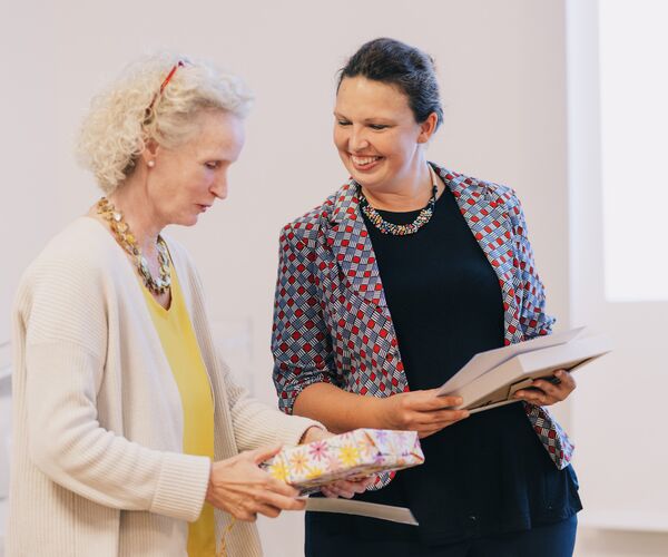 Zwei Frauen: links mit hellen Haaren, weißer Strickjacke und gelber Bluse. rechts mit dunklen Haaren, blau-rotem Blazer und schwarzer Bluse, © Frank Herzmann