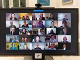 Foto eines Bildschirms, auf denen 25 Gesichter von Menschen zu sehen sind, die sich in einer Videokonferenz befinden, unten rechts auch Erzbischof Becker. Viele heben Sektgläser hoch.
