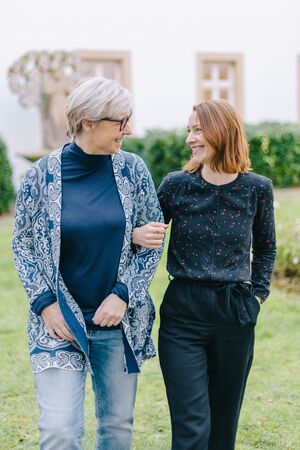 Zwei Frauen: links mit blau gemusterter Jacke, blauem Shirt darunter, hellen, kurzen Haaren und Brille. Rechts mit dunkelblauem Shirt und braunroten, schulterlangen Haaren. © Frank Herzmann